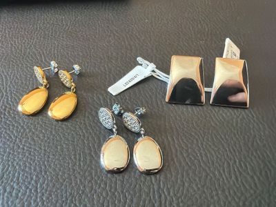 two pairs of earrings and a tie bar on a table