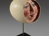 sculpture représentant le visage d'une femme dans une coquille d'œuf, posée sur un socle noir