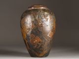 a brown vase with a design on it sitting on a table