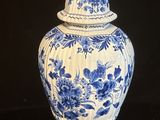 un vase bleu et blanc surmonté d'un oiseau