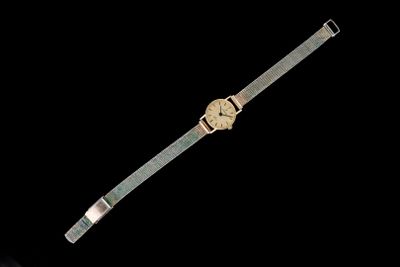 une image représentant une montre-bracelet posée sur une surface noire, sur fond noir