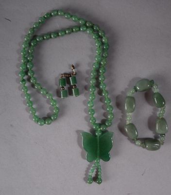 collier, bracelet et bague composés de perles de jade sur un fond blanc