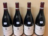 four bottles of red wine are lined up on a wooden box