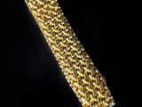 a close up of a gold bracelet on a black background