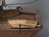 a wooden model of a sailboat with a surfboard on it