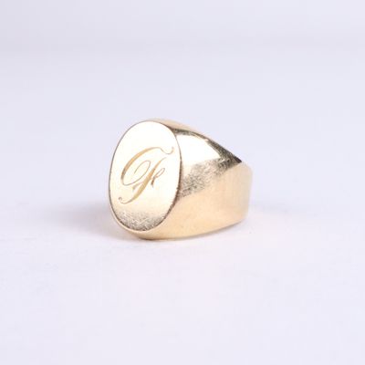 the gold signet ring with the letter g on it