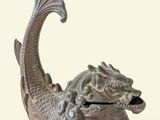 statue of a fish with its mouth open sitting on top of a bowl