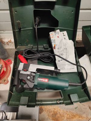 une boîte à outils verte posée par terre, contenant des outils