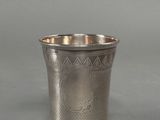une coupe ancienne en argent, ornée d'un motif sur le bord, sur fond gris