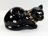 une figurine représentant un chat noir posée sur une surface blanche