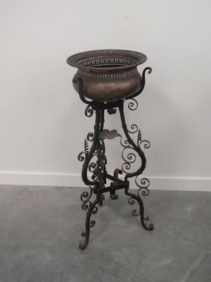 un tabouret ancien en fonte, avec une assise en cuir marron et un piètement en métal