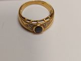 a close up of a gold ring with a black stone on it