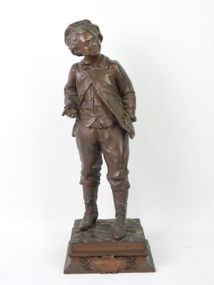 statue en bronze représentant un garçon debout sur un socle, les mains dans les poches