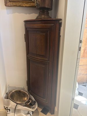 a wooden cabinet in the corner of a bathroom