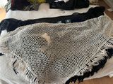 a white crochet bag on a bed next to a black and white blanket