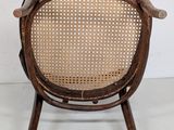 an old wooden chair with a woven seat on a white floor