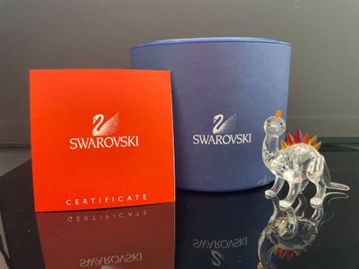 un petit animal en verre posé à côté d'une boîte de Swarovski