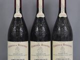 Trois bouteilles de vin rouge sont alignées sur une table en verre