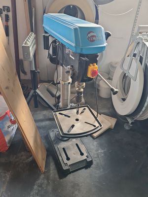 une perceuse posée sur un support dans une pièce où se trouvent de nombreux outils