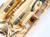 the saxophone is shiny gold and has a black knob