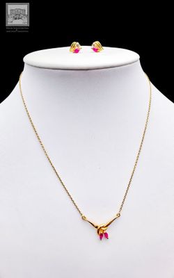 un collier et des boucles d'oreilles en or sertis de pierres roses, présentés sur un mannequin