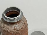 a small jar with a lid next to a coin