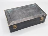 a small black box with a gold handle on a white surface