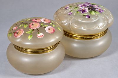 une paire de boîtes en verre ornées de fleurs peintes, posées sur une table