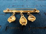 an image of a gold broochle with three bells on it