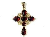 un gros plan d'un pendentif en forme de croix orné de grenats, sur fond blanc