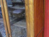 a wooden cabinet with a glass door in the corner of the room