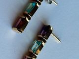 a pair of earrings with multi colored stones on a white surface