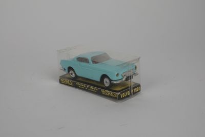 une petite voiture bleue dans une boîte transparente posée sur une surface blanche