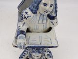 a blue and white figurine of a woman reading a book