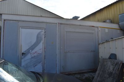 une voiture garée devant un immeuble dont la porte est ouverte