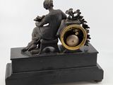 a black clock with a man sitting on top of it