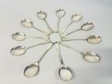 six silver spoons arranged in a circle on a white surface