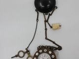 a clock that is attached to a chain on the wall
