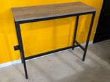 une table en bois avec des pieds en métal, adossée à un mur jaune