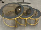 trois tables avec un plateau en verre et un piètement doré dans une pièce