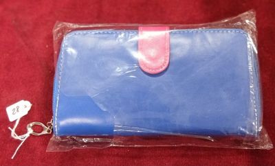 un petit portefeuille bleu avec une poignée rose sur un fond rouge