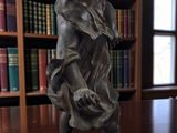 a statue of a boy sitting on a table in a library