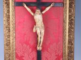 an old wooden crucifix with a red wall behind it
