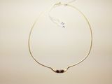 a close up of a gold necklace with a black bead on it