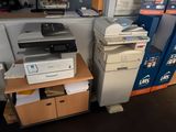 une imprimante posée sur un bureau, à côté d'une pile de cartons