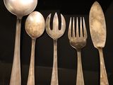 five spoons, a fork, and a spoon on a black surface