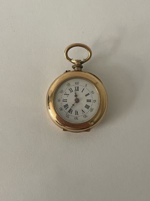 une petite montre de poche en or avec des chiffres romains