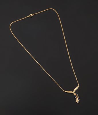 a gold plated necklace with a bird pendant on a black background