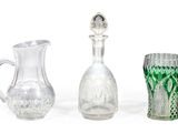trois vases en verre et un pichet en verre posés sur une surface blanche