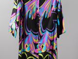 a black shirt with multicolored leaves on it hangs on a hanger